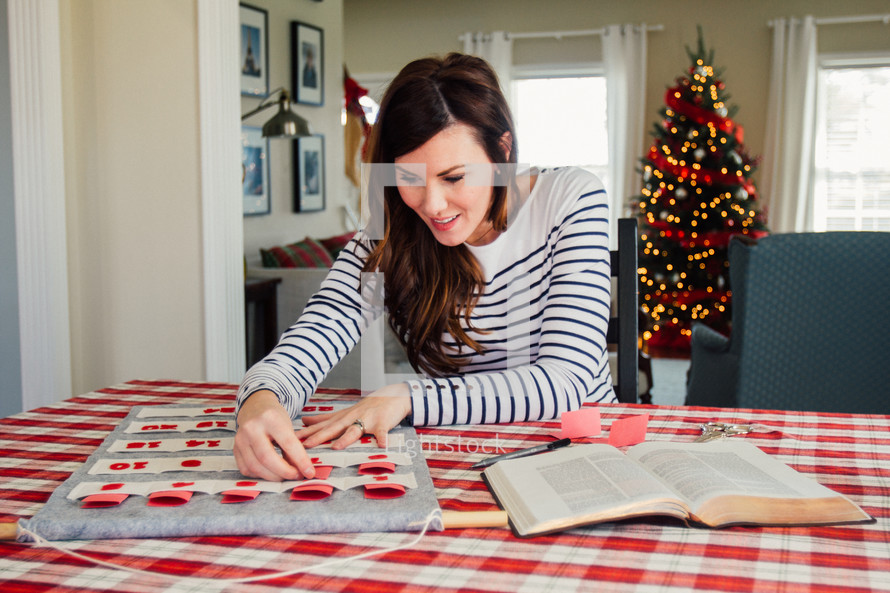 a woman writing Bible verses on an Advent calendar 