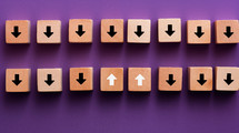 Arrows pointing down with two arrows pointing up on a purple background. Against the grain concept. 