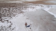 person hiking a dry lake bed 