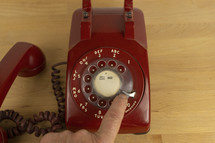 A man dialing the operator on a vintage rotary phone