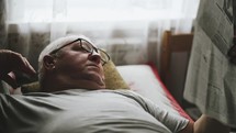 A mature man in glasses reading a newspaper at home. Senior Adult Reading Newspaper Leisure Concept.