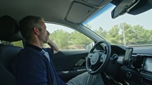 Male driver sitting in an autonomous car, letting the car drive by itself