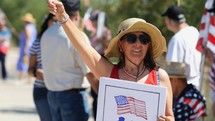 A patriotic woman waving the American flag at a rally