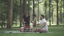 Portrait of Small and Happy Asian Family Enjoying Activities at The Park - Picnic and Cooking - Father, Mother and Child in Slow Motion