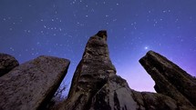 time-lapse of stars in the night sky over jagged rock formations 