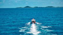 Wooden boat in turquoise sea, movement on blue water. Trip boat with tourists sailing on clean blue sea surface. A long-tailed Thai boat sails among the islands, touristic excursion ride. Aerial. 