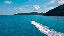 Wooden boat in turquoise sea, movement on blue water. Trip boat with tourists sailing on clean blue sea surface. A long-tailed Thai boat sails among the islands, touristic excursion ride. Aerial. 