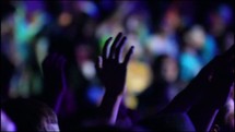 Audience with hands raised at a worship concert.