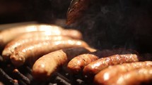 Sausages being turned on a grill.