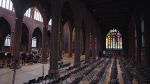 The interior of Manchester Cathedral filled with Gothic-themed ornaments such as stained glass windows and statues.