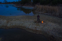 Aerial shot of a man building a fire at sunset on a cold day.