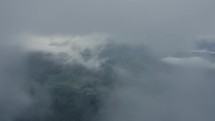 Aerial shot of clouds and green mountains flying through clouds and valleys with drone 