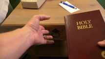 A man taking a Gideon Bible out of a hotel room drawer