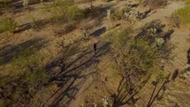 Aerial of a woman hiking on a trail through the desert