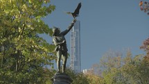 The Falconer Sculpture a man reaching upwards to release his hunting bird and Central Park Tower Manhattan, New York City, USA