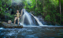 Tourist man with backpack at the waterfall