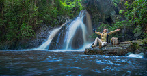 Tourist man with backpack sit and relax at the waterfall
