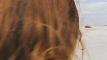 woman walking on a beach with hair blowing in the sea breeze 