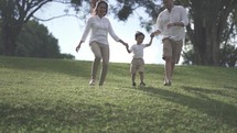 Portrait of Small and Happy Asian Family Enjoying Activities at The Park - Father, Mother and Child in Slow Motion