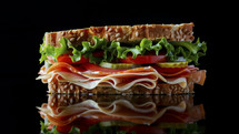 Freshly made deli sandwich with layered ingredients on a reflective surface.