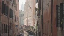 The atmosphere of narrow canals in the city of Venice, with many bridges and small boats parked.