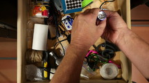 A man looking through the junk drawer in the kitchen