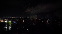 Fireworks over water with boats watch