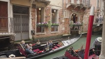 The atmosphere of narrow canals in the city of Venice, with many bridges and small boats parked.