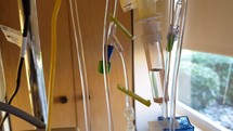 Many IV tubes hanging from a stand in a hospital room