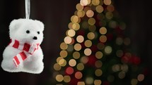 Small polar bear decoration with blurred Christmas tree 
