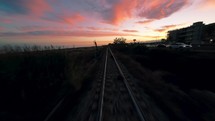 Following a railway near a sea with sunset sky 