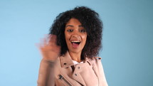 Young African American black woman waving hand hello. Greeting, say Hi to camera. Beautiful young mixed race trendy girl with afro hairstyle.