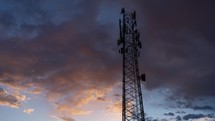 Time lapse of colorful clouds beyond a communications tower