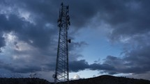 Time lapse of clouds over a communications tower at dusk