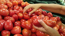 A woman buying fresh tomatoes at a grocery store