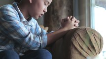 a praying child sitting on a chair 
