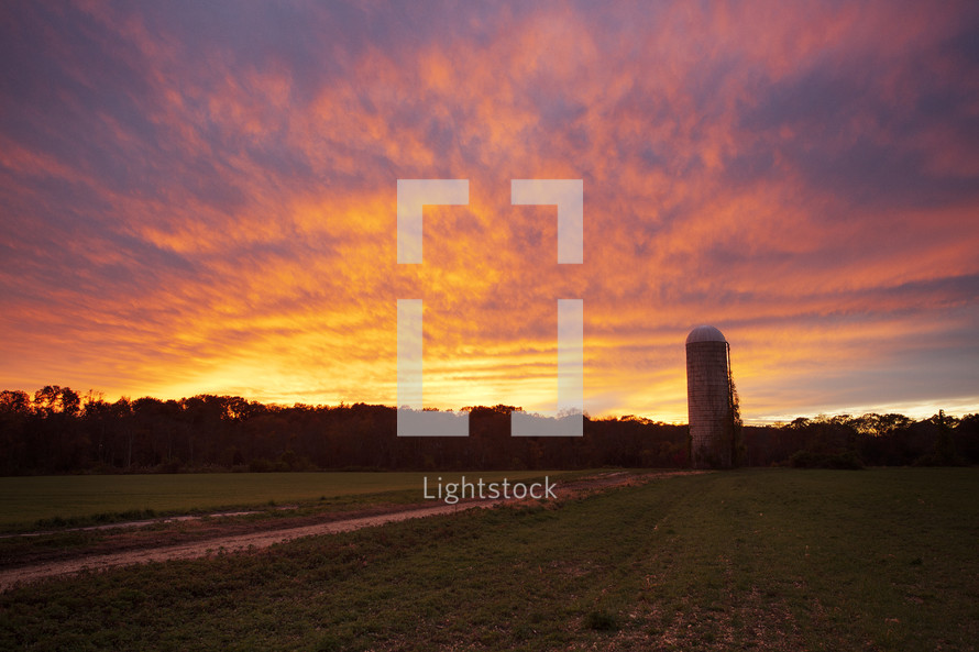 a silo on farmland at sunset 