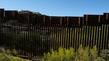 A panning shot of the fence at the US - Mexico border