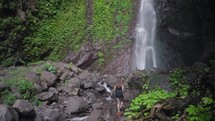Woman Female Exploring Les Waterfall (Yeh Mempeh or Flying Waterfalls) in Tejakula Village, Buleleng, Bali - Secluded Cascade Surrounded by Rainforest, Cliffs Overgrown with Green Tropical Plants