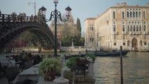 The tourists are enjoying wine in the late afternoon at a romantic restaurant by the side of the Grand Canal in Venice and beside the Ponte dell'Accademia.