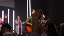 Hands raised in front of blurred worship band