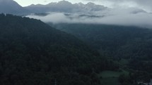 Aerial shot of clouds and green mountains flying through clouds and valleys with drone 
