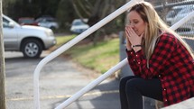 a woman sitting on steps in public crying 