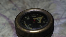 An old compass pointing to North with a map background