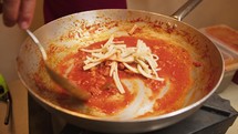 Preparing pasta with sauce.