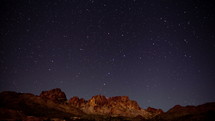 Timelapse of stars rising above jagged desert mountains
