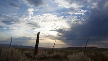 Tracking timelapse of summer clouds beyond a ranch fence