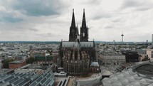 Aerial drone footage circling the Cologne Cathedral along the shore of the Rhine River in Germany.