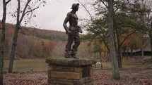 Statue of unemployed members CCC in Devil's Den State Park Cascade Waterfalls and River Lake during Autumn Fall Foliage Arkansas USA