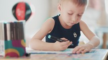 Drawing. Little boy with pencil coloring at home. Child draws at the table. Psychology of the child's personality. Help gaining confidence. Creativity and education concept.